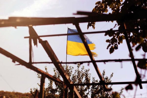Hilfe für die Ukraine: Ein ukrainische Fahne weht über einem Dachgitter an einem Garten