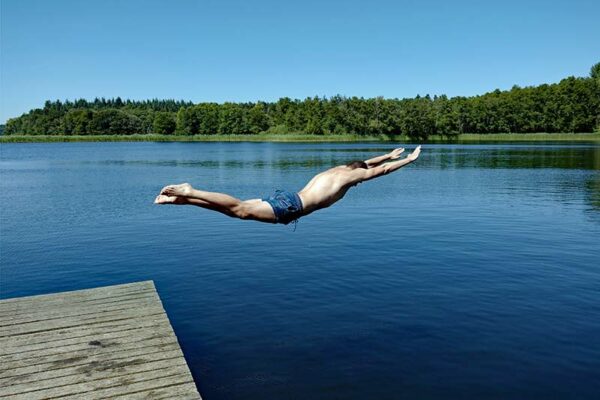 Ein Mann springt in Badehose in einen See. Das symbolisiert das Thema Reanimation nach Badeunfällen