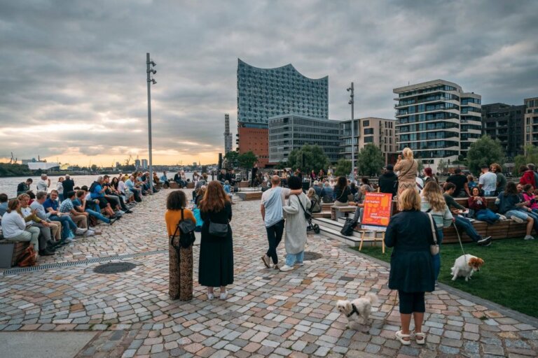 Am Strandhöft spielt eine Band, im Hintergrund die HafenCity im Forderung Zuschauer beimSunset Sound Elbsommer