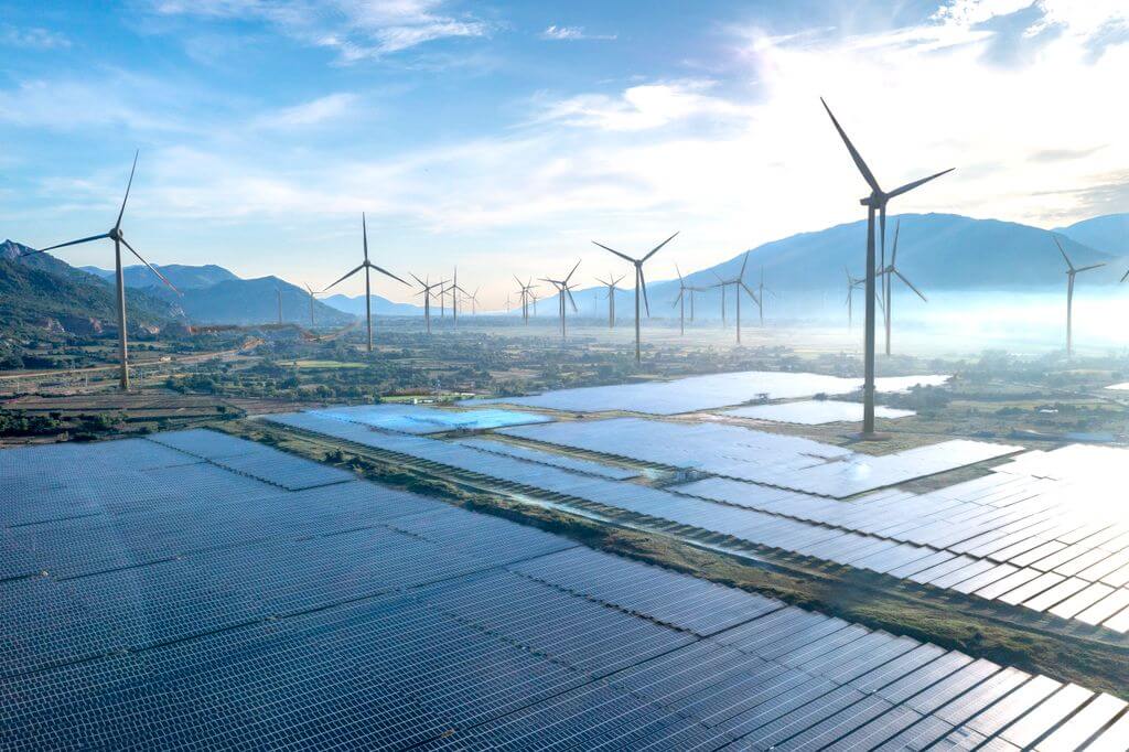 Windräder und Photovoltaik zur Stromerzeugung in einem weitläufigen Tal im Sommer