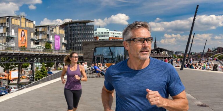 Glasklare Sicht beim Sport. Ein Mann und eine Frauen laufen auf der Promenande am Hamburger Hafen mit einer Sportbrille. Bild von DALL:E